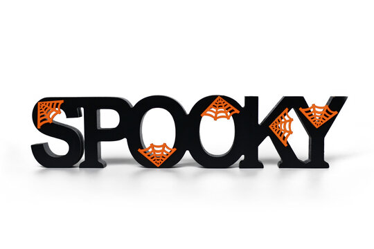 Halloween decor wooden letters saying 'Spooky' with orange cobwebs on white background