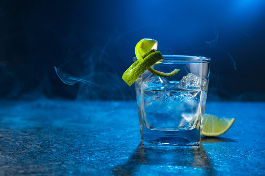 Vodka with lime and ice cubes in a fogged up glass.
