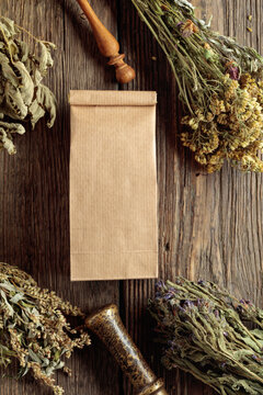 Brown paper bag and bundles of dried medicinal herbs on an old wooden table.