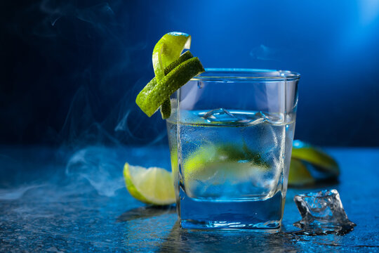 Vodka with lime and ice cubes in a fogged up glass.
