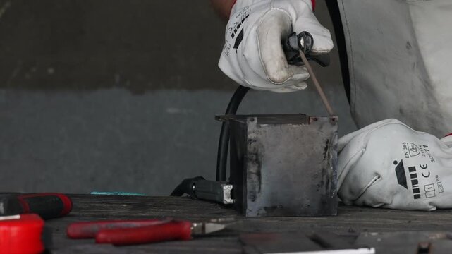 Professional welder in white safety gloves welding steel component with bright arc flash and sparks