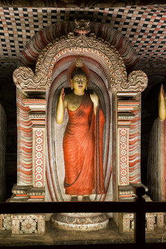 Standing Buddha Statue Adorned in Red Robe Within Dambulla Cave Temple