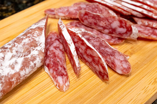 Sliced fuet sausage on wooden board closeup