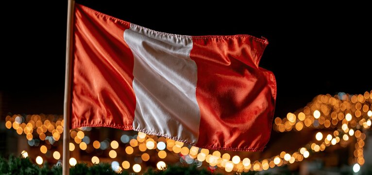 The Peruvian flag waves brightly over a lively city at night, symbolizing national pride and heritage.