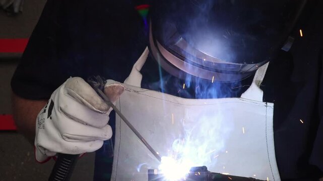 Welder performing manual arc welding process creating bright light flash in dark workshop