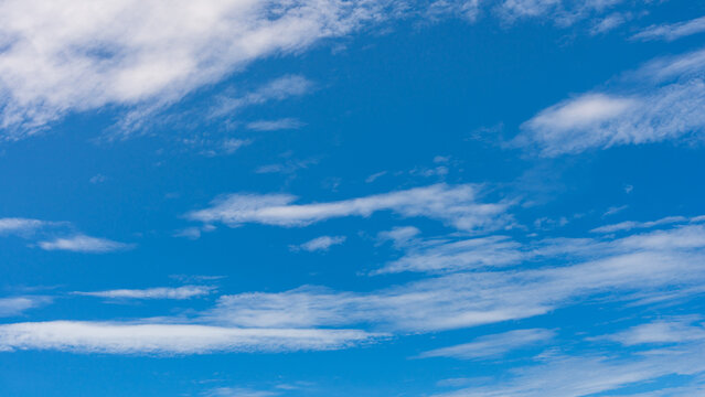 Vast clear blue sky streaked with thin, elongated wispy clouds stretching horizontally across the frame.