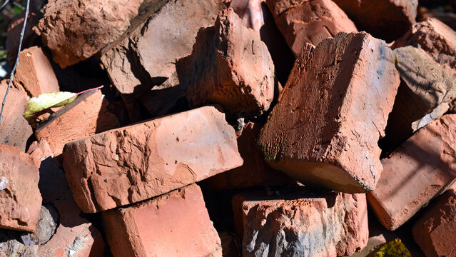 old brick. red brick. a haphazardly thrown pile of old broken bricks. a concept of a ruin, a war or natural disaster, construction, renovation. building materials, dismantling. for background. closeup