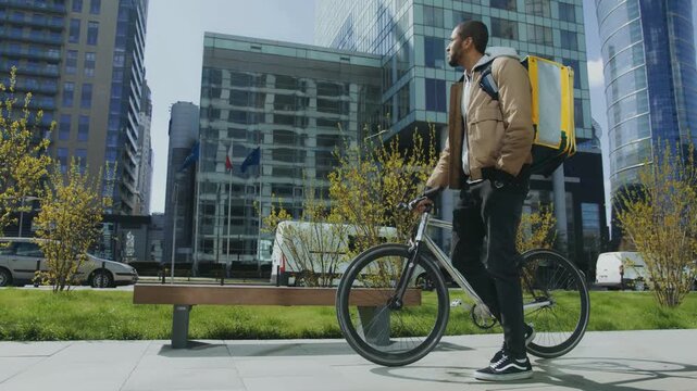 Urban delivery man walking bicycle through modern city business district