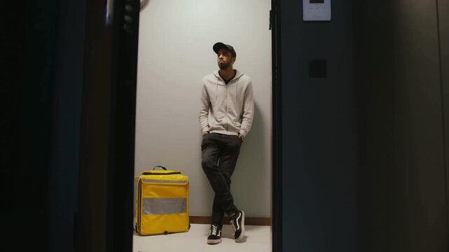 Young delivery courier standing with yellow insulated food delivery bag