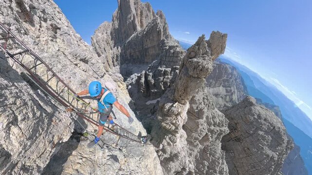 Climber ascending Scala degli Amici with spectacular Brenta Dolomites panorama on Via Ferrata Bocchette Alte