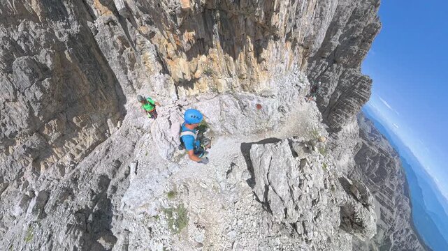 Two hikers traversing dramatic exposed ledges on the Maria Foresti section of Via Ferrata Bocchette Alte