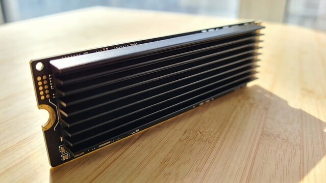 Macro Shot of M.2 NVMe SSD with Black Aluminum Heatsink for Thermal Cooling on Wooden Surface