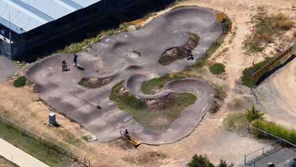 Obraz premium Aerial View of Cyclists on a Winding Asphalt Pump Track