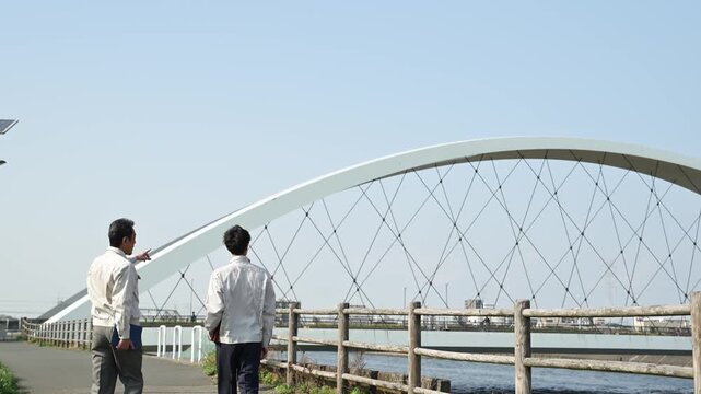 橋梁工事の現場で指差しをしながら歩く30代と50代の作業員