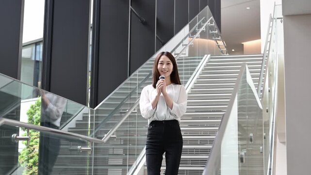 ピンマイクを持って歩きながらプレゼンテーションをする20代の日本人女性