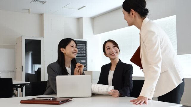 会議で笑顔を見せながら打ち合わせをする20代から40代の日本人ビジネスパーソン3人