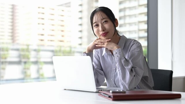 窓際でノートパソコンを使って仕事をする30代の日本人ビジネスパーソンの女性