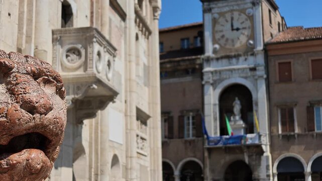close-up of weathered stone lion statue with its mouth open. Serving as pillar base outside historic San Geminiano cathedral. Highlighting rich Italian architectural heritage and town hall bell tower