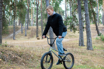 Obraz premium Teenage Boy Riding and Performing Tricks on a BMX Bike in Pine Forest Park