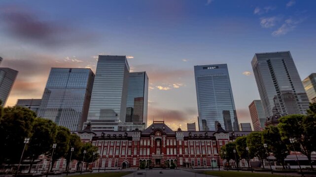 早朝の東京駅周辺の高層ビル街の背景に広がる朝焼け空（丸の内行幸通りから八重洲方面を臨むハイパーラプス映像）