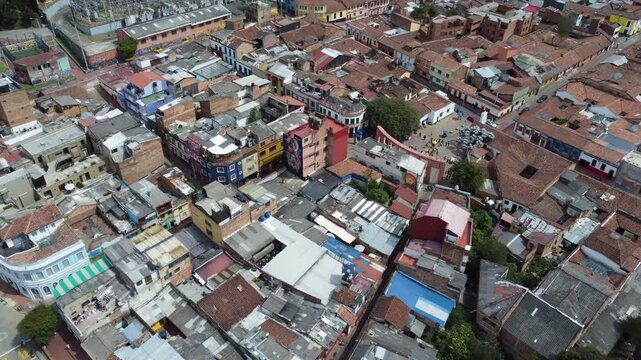 Wide aerial tilt down view of colorful colonial buildings and the Chorro de Quevedo Plaza in La Candelaria, Bogot&aacute;