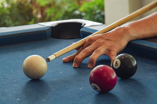 Open bridge hand holding cue stick aiming carefully cue white billiard balls, capturing focus targeting and concentration stance pose for casual snooker recreation activity at home entertainment