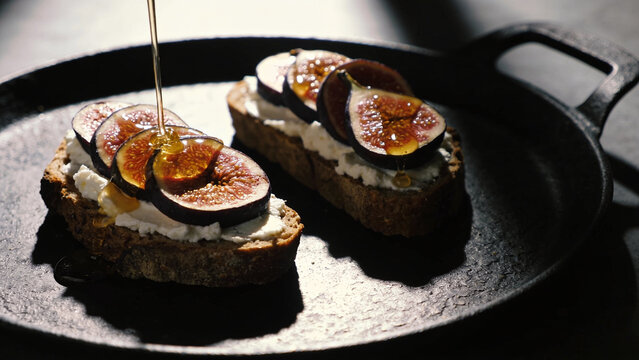 Moody low angle shot of rustic crostini with fresh figs goat cheese and honey drizzle