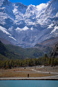 Hiker standing on the shore of Blue Lake near Manang with majestic snow-capped mountains, Annapurna Circuit, Nepal