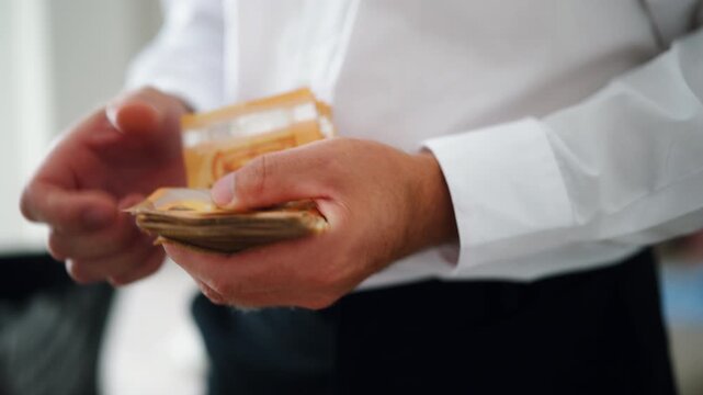 Close-up of male hands counting large bundle of fifty euro banknotes, representing cash, wealth, financial transactions, payment, profit, income and business finance