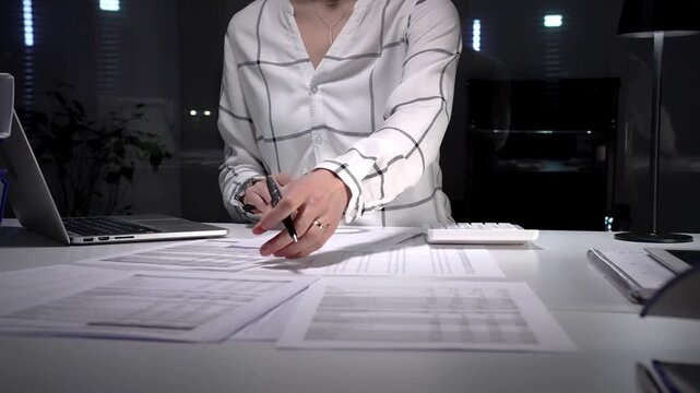 Professional woman uses magnifying glass and pen to scrutinize financial reports and documents on an office desk, symbolizing auditing, investigation and detailed data analysis