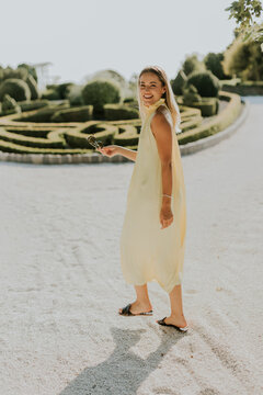 Woman in a yellow dress strolls happily through a lovely garden