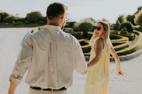 Happy couple exploring a beautiful garden in bright sunlight holding hands