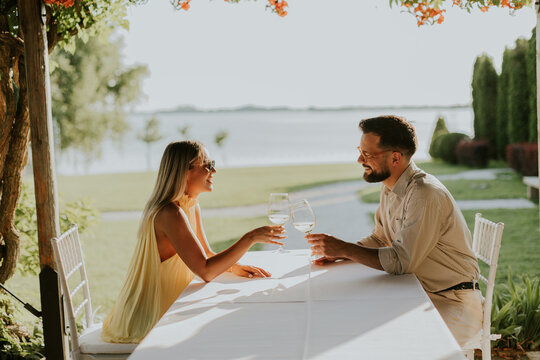 Couple enjoys a sunny afternoon with drinks by the lake