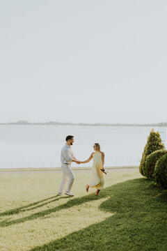 Joyful couple dancing by the serene lake under the sunny sky