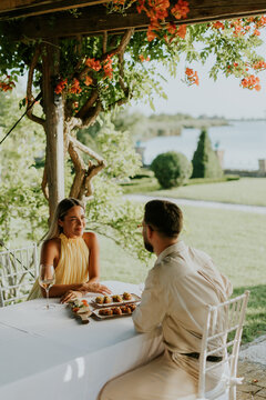Couple enjoying a romantic meal by the waterfront under blooming flowers