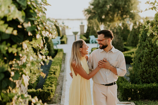 Joyful couple sharing a romantic moment in a sunlit garden pathway