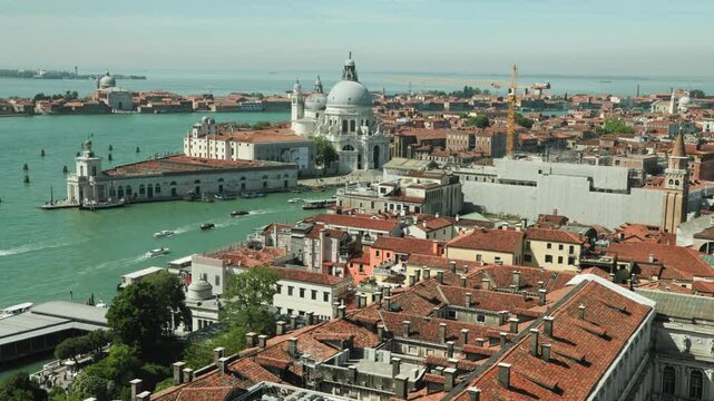 Boats navigate the Grand Canal past terracotta rooftops towards the majestic Santa Maria della Salute basilica. An iconic cityscape inspiring romantic summer vacations and luxury travel.
