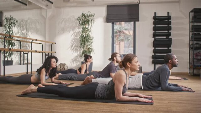 Instructor conducting yoga session. Multicultural people doing yoga lesson. Multiethnic men and women in sportswear. Spiritual union with inner world. People lying on mats and doing yoga pose.