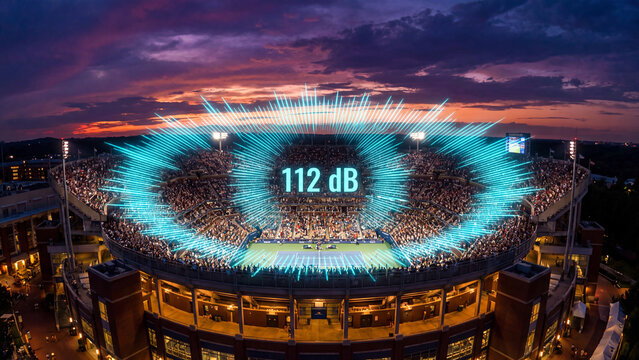 Sports stadium filled with a cheering crowd at sunset displays a glowing digital sound wave graphic highlighting the intense noise level of 112 decibels.