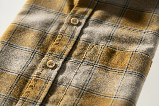 Yellow plaid flannel shirt close up, soft cotton checkered fabric texture, vintage button down lumberjack shirt detail, warm autumn fashion textile