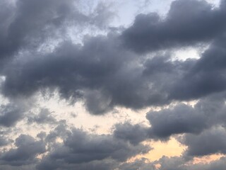 Obraz premium Beautiful dramatic sunset sky with dark fluffy clouds and soft orange gradient. Serene atmospheric twilight landscape with ample copy space.