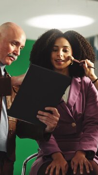 Director, talk and model in studio with clipboard, catalog and change script for production. People, stylist and makeup in bts with document, producer advice and review dialogue for filming briefing