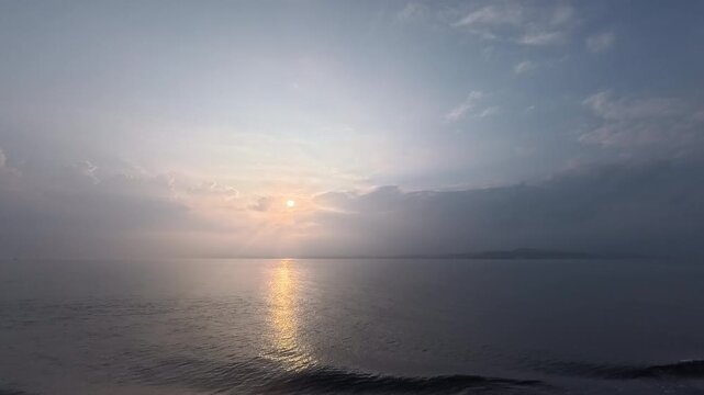 Stunning maritime landscape featuring a bright sun through atmospheric haze and gentle ripples