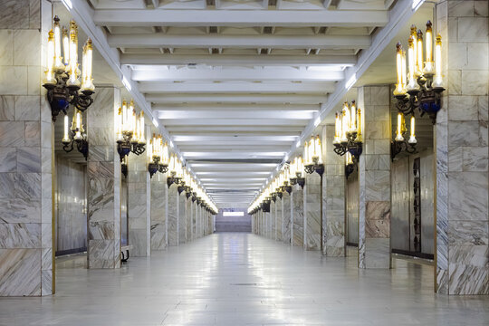 Ornate marble Pushkin metro station hall in Tashkent with symmetrical columns, golden chandeliers. Empty underground corridor showcases Soviet-era grandeur and polished stone surfaces, ideal travel.