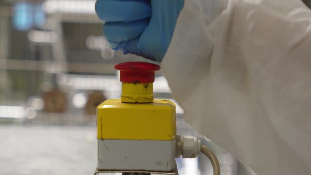 Emergency stop button forcefully pressed by fist, slow motion
