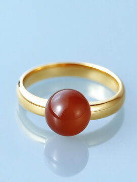 Gold ring with fire opal gemstone showcasing vibrant red hue. Luxury jewelry detail featuring polished cabochon cut and reflective surface.
