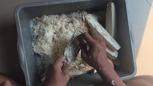 the process of manually grating cassava to get a coarse texture