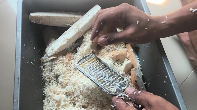 the process of manually grating cassava to get a coarse texture