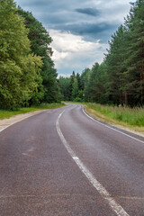 Fototapeta premium Overcast Summer Day on Two-Lane Rural Highway Through Pine Forest, Central Russia