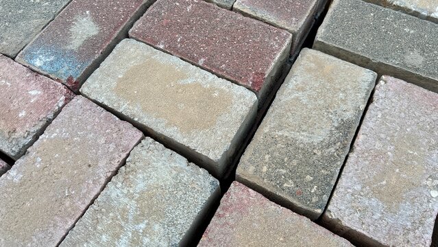 Closeup of interlocking concrete paving stones with weathered textured surface, geometric pattern and colorful rectangular brick pavement background